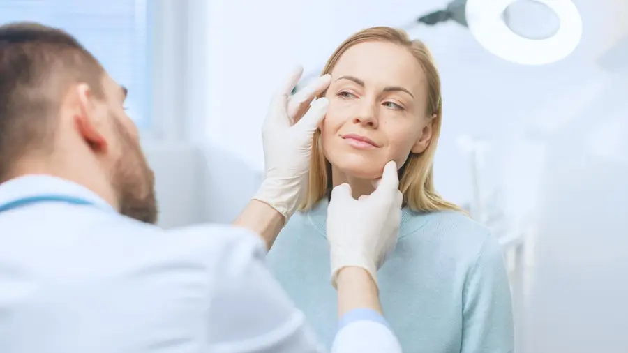 Dentista avaliando o rosto de uma paciente antes de um procedimento de harmonização orofacial.